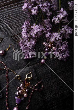 author collection jewelry with lilac gemstones, crystals and pearls demonstrated at black stones background. fashion and jewelry concept. flat lay author collection jewelry with lilac gemstones, crystals and pearls demonstrated at black stones background. fashion and jewelry concept. flat lay 103571023