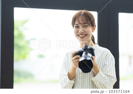 カメラを構える笑顔の女性 103571184