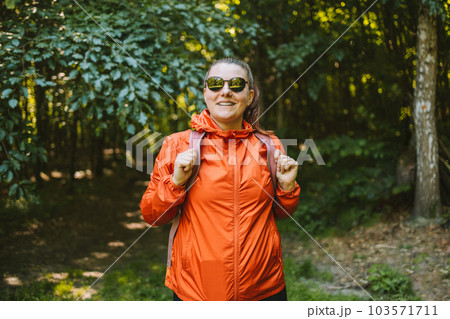Young happy 30s woman hiking and going camping in nature. Person with backpack walking in the forest 103571711
