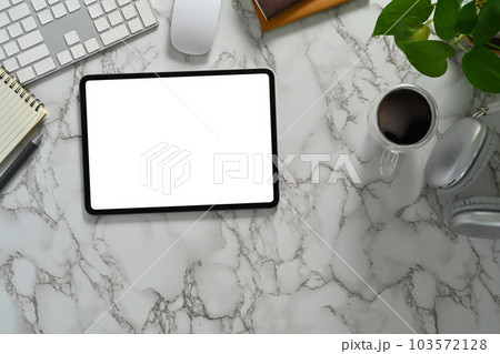 Flat lay, top view of digital tablet with empty dimply, coffee cup, notebook and potted plant on marble table 103572128