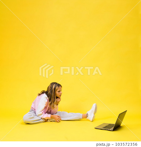 Positive kid sit with laptop read homework wear casual style cloth isolated over yellow background 103572356