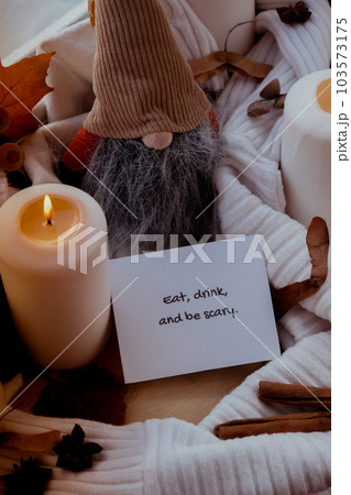 EAT DRINK AND BE SCARY text greeting card concept Celebrating autumn holidays at cozy home on the windowsill Hygge aesthetic atmosphere Autumn leaves spices and candle on knitted white sweater in warm EAT DRINK AND BE SCARY text greeting card concept Celebrating autumn holidays at cozy home on the windowsill Hygge aesthetic atmosphere Autumn leaves spices and candle on knitted white sweater in warm 103573175
