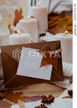 Empty paper note copy envelope space for your text on background of aesthetic atmosphere Autumn leaves spices and candle on knitted white sweater in warm yellow lights. Still life. Raining Empty paper note copy envelope space for your text on background of aesthetic atmosphere Autumn leaves spices and candle on knitted white sweater in warm yellow lights. Still life. Raining 103573179