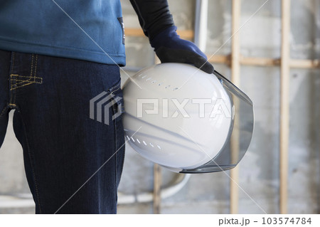 建築現場にヘルメットを抱えて立つ作業員男性手元 103574784