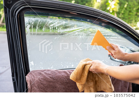 Using squeegee blade cleaning old car window film tint 103575042