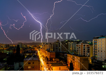 Lightning storm over city in purple light 103576072