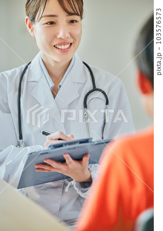 小学生の男の子に問診をする若い女性医師 103576573
