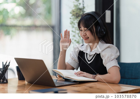 Online education, e-learning. Asian woman in stylish casual clothes, studying using a laptop, listening to online lecture, taking notes, online study at home Online education, e-learning. Asian woman in stylish casual clothes, studying using a laptop, listening to online lecture, taking notes, online study at home 103578870
