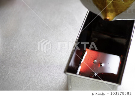 プリンのカラメルソースを型に流し込む プリンのカラメルソースを型に流し込む 103579393
