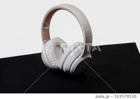 Beige wireless headphones on a dark background. Accessory for listening to music. Isolate. 103579530