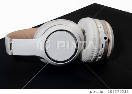 Beige wireless headphones on a dark background. Accessory for listening to music. Isolate. Beige wireless headphones on a dark background. Accessory for listening to music. Isolate. 103579538