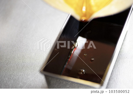 プリンのカラメルソースを型に流し込む プリンのカラメルソースを型に流し込む 103580052