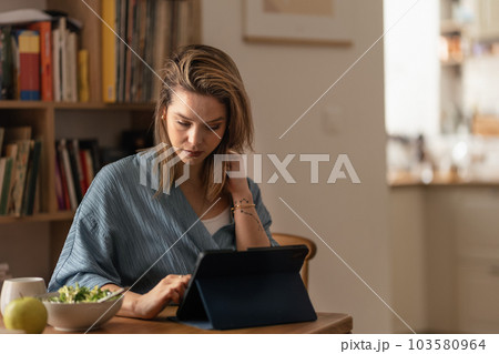 Portrait of young woman in her apartment working on laptop. Portrait of young woman in her apartment working on laptop. 103580964