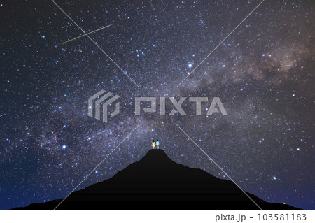 山頂で満天の星空を見上げるカップル。星空デート。 山頂で満天の星空を見上げるカップル。星空デート。 103581183