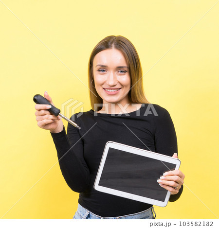 Service center. Laptop Repair. Female screwdriver unscrews laptop bolts on yellow background 103582182