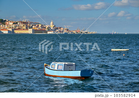 View of Lisbon over Tagus river from Almada with blue fishing boat and yachts tourist boats in background at sunset. Lisbon, Portugal 103582914