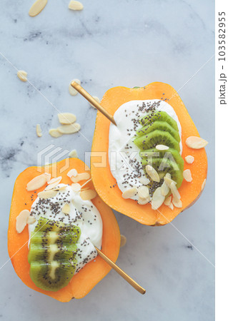 Yogurt papaya boat with kiwi, chia seeds and almonds. Healthy summer food. Yogurt papaya boat with kiwi, chia seeds and almonds. Healthy summer food. 103582955