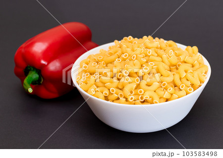 Uncooked Chifferi Rigati Pasta in White Cup and Red Bell Pepper 103583498