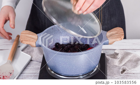 Step by step. Preparing mixed berry compote from frozen berries in a nonstick cooking pot. 103583556