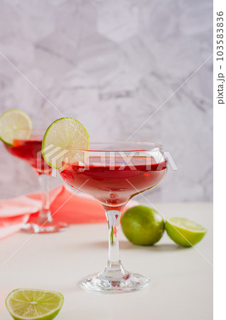 Cosmopolitan cocktail with lime in glasses on the table vertical view Cosmopolitan cocktail with lime in glasses on the table vertical view 103583836