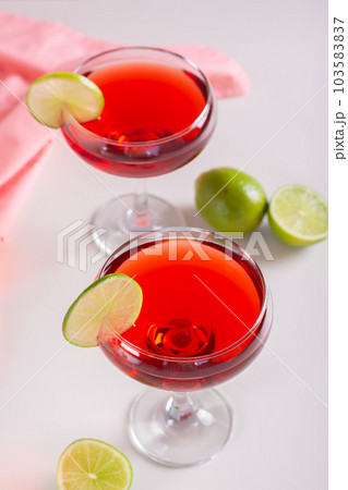 Alcoholic cosmopolitan cocktail in glasses and lime on the table vertical view 103583837