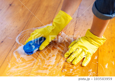 Woman in rubber gloves is using floor brush to cleaning floor 103583959