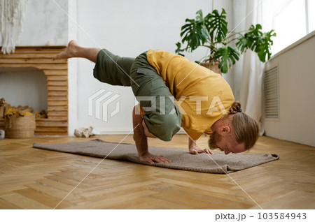 Man practicing hand standing yoga pose at home living room Man practicing hand standing yoga pose at home living room 103584943