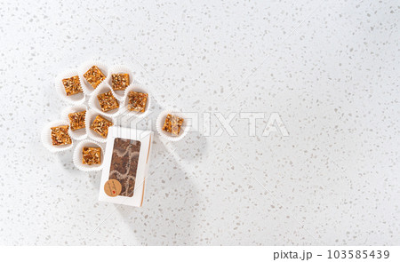 Flat lay. Packaging homemade pumpkin spice fudge with pecans into a white paper gift box. 103585439