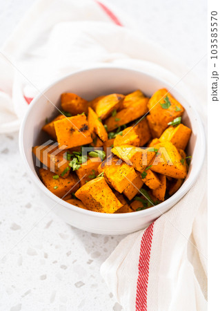 Serving oven-roasted sweet potatoes in a white ceramic bowl. 103585570