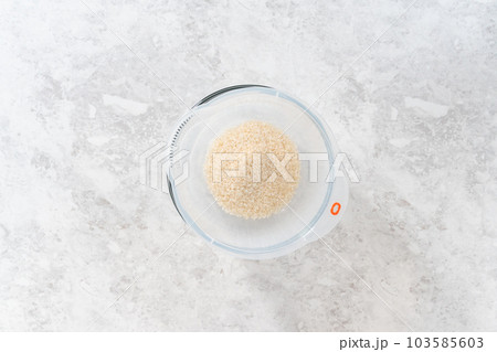 Flat lay. Washing dry rice in a rice washer and large glass bowl. 103585603
