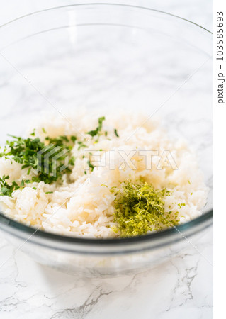 Cilantro Lime Rice. Mixing ingredients in a glass mixing bowl to prepare cilantro lime rice. 103585693