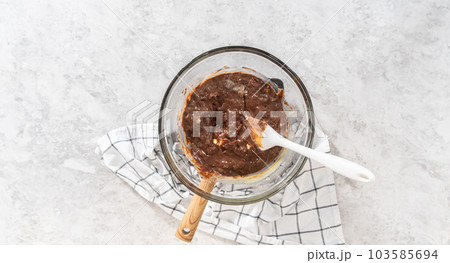 Flat lay. Melting white chocolate chips and other ingredients in a glass mixing bowl over boiling water to prepare chocolate macadamia fudge. Flat lay. Melting white chocolate chips and other ingredients in a glass mixing bowl over boiling water to prepare chocolate macadamia fudge. 103585694