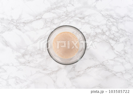 Flat lay. Mixing ingredients in a glass mixing bowl to bake homemade brioche buns. 103585722