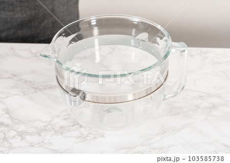 Mixing ingredients in a glass mixing bowl to bake homemade brioche buns. 103585738