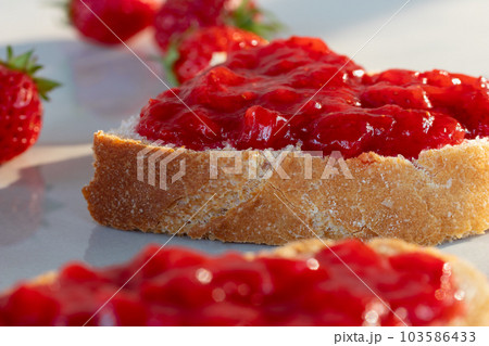 Wheat bread toasts with spread strawberry jam on the table, closeup 103586433
