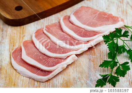 Raw pork chops on wooden surface with parsley 103588197