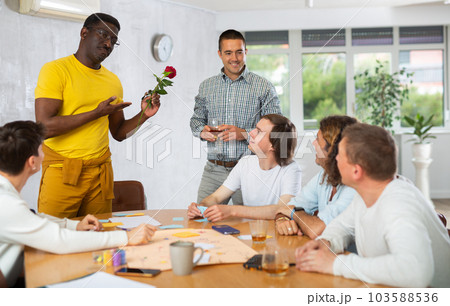 African American man giving rose to boyfriend during friendly get-togethers 103588536