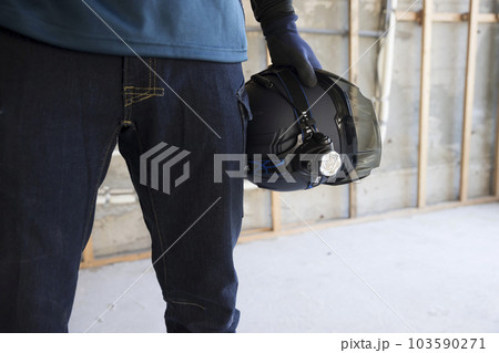 建築現場にヘルメットを抱えて立つ作業員男性手元 103590271