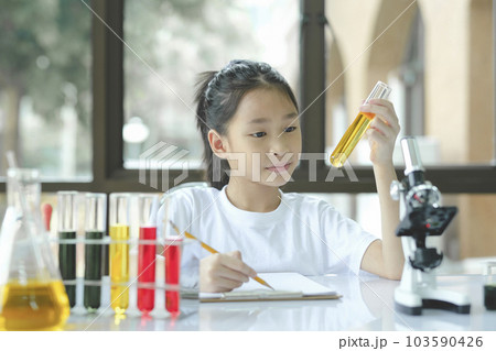 preschool girl is interested in laboratory lesson, taking notes on book for her study. 103590426