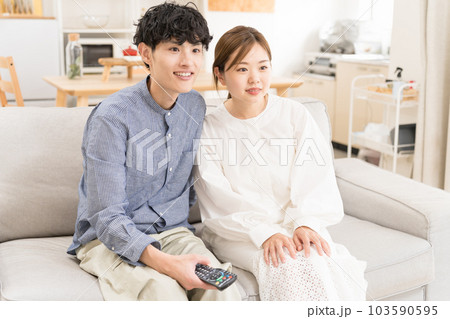ソファーに座ってリモコンを手に持ってテレビ鑑賞している夫婦 ソファーに座ってリモコンを手に持ってテレビ鑑賞している夫婦 103590595