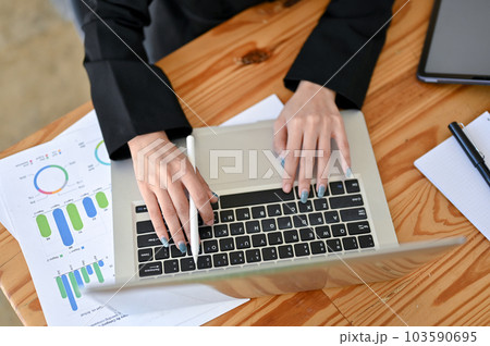 Top view of a businesswoman using her laptop and analyzing financial data at her desk. 103590695