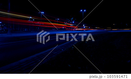 Lights of cars at night. Street line lights. Night highway city. Long exposure photograph night road. Colored bands of red light trails on the road. Background wallpaper defocused Lights of cars at night. Street line lights. Night highway city. Long exposure photograph night road. Colored bands of red light trails on the road. Background wallpaper defocused 103591471