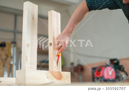 Caucasian man assembles the table with a screwdriver. Close-up of a carpenter's hands. Caucasian man assembles the table with a screwdriver. Close-up of a carpenter's hands. 103592707