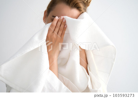 The girl wipes her face with a terry towel. The girl wipes her face with a terry towel. 103593273