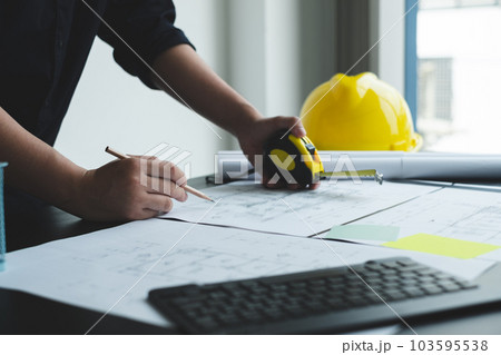 Architects or engineers working construction and drawing construction plans, printing, writing on-site construction sites. Home design concept Architects or engineers working construction and drawing construction plans, printing, writing on-site construction sites. Home design concept 103595538