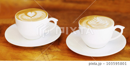 Latte, retro and coffee cup on brown wooden table at a restaurant to drink expresso in the kitchen. Cafe, coffee and vintage background and espresso aroma with milk and cozy house for breakfast Latte, retro and coffee cup on brown wooden table at a restaurant to drink expresso in the kitchen. Cafe, coffee and vintage background and espresso aroma with milk and cozy house for breakfast 103595801