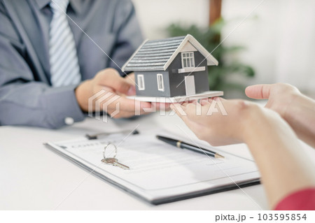 Real estate agent broker hand over the home to the new owner after completing the signing according to agreement renting a house and buy house insurance Home insurance concept 103595854