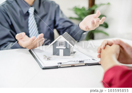 A real estate agent with House model is talking to clients about buying home insurance. Home insurance concept 103595855