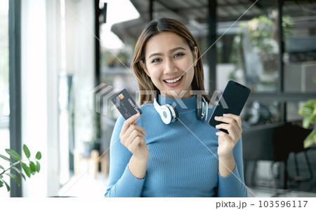 Asian girl shopping online holding credit and using smartphone enter their card number in the mobile phone app to purchase and payment in internet store 103596117