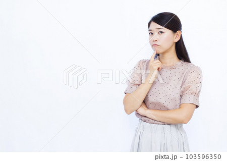 白い背景の前で真剣に悩んでいる30代の女性 103596350